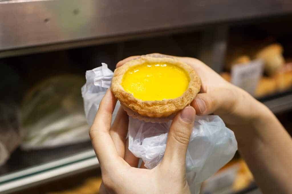A person holding a pastry with a yellow filling.