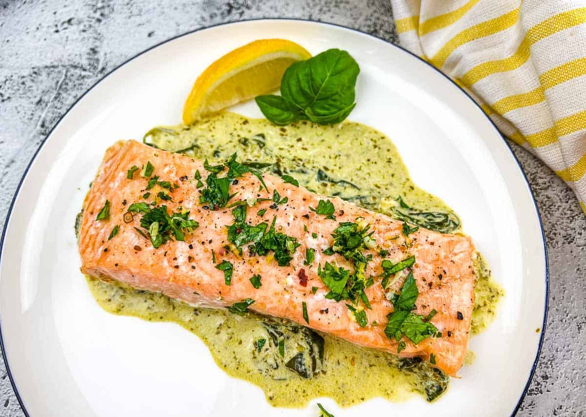 Salmon with spinach sauce on a white plate.