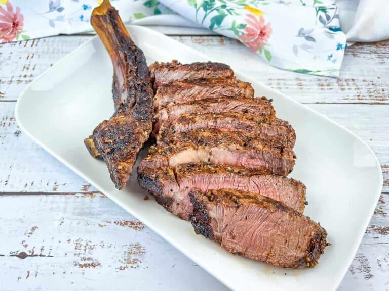 A sliced tomahawk steak on a white plate.