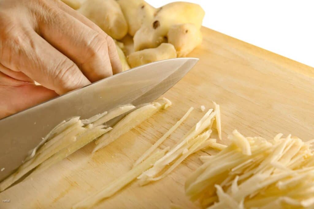 A person cutting ginger on a cutting board.