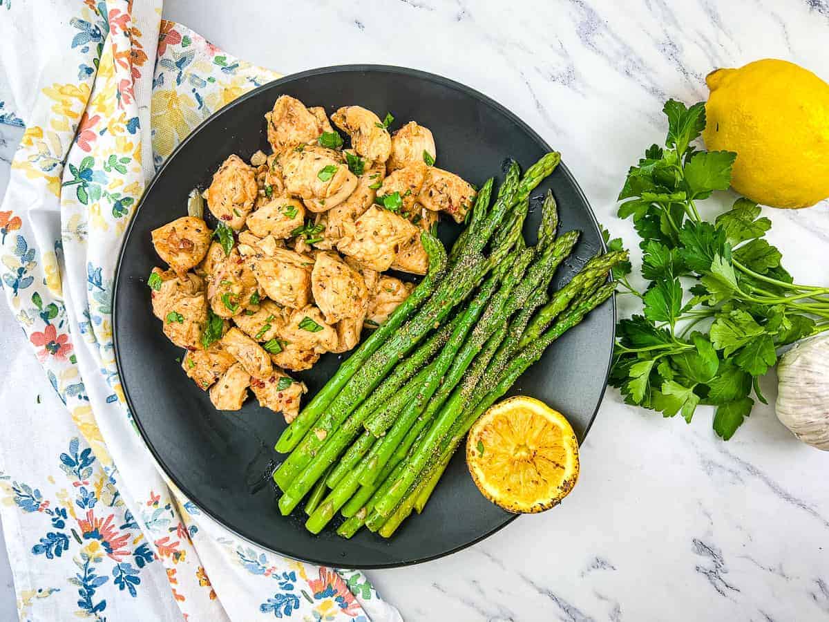 A plate of Garlic Butter Chicken Bites with asparagus. 