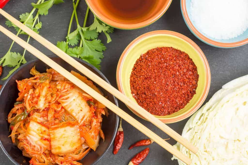 A bowl of korean food and chopsticks.