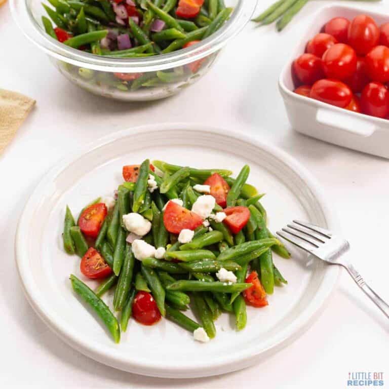 Green beans and tomatoes on a white plate.