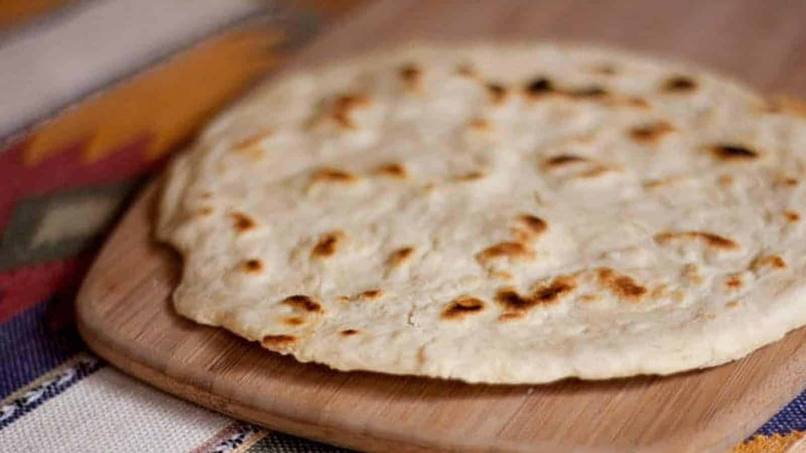 Flour tortillas stacked on a plate.
