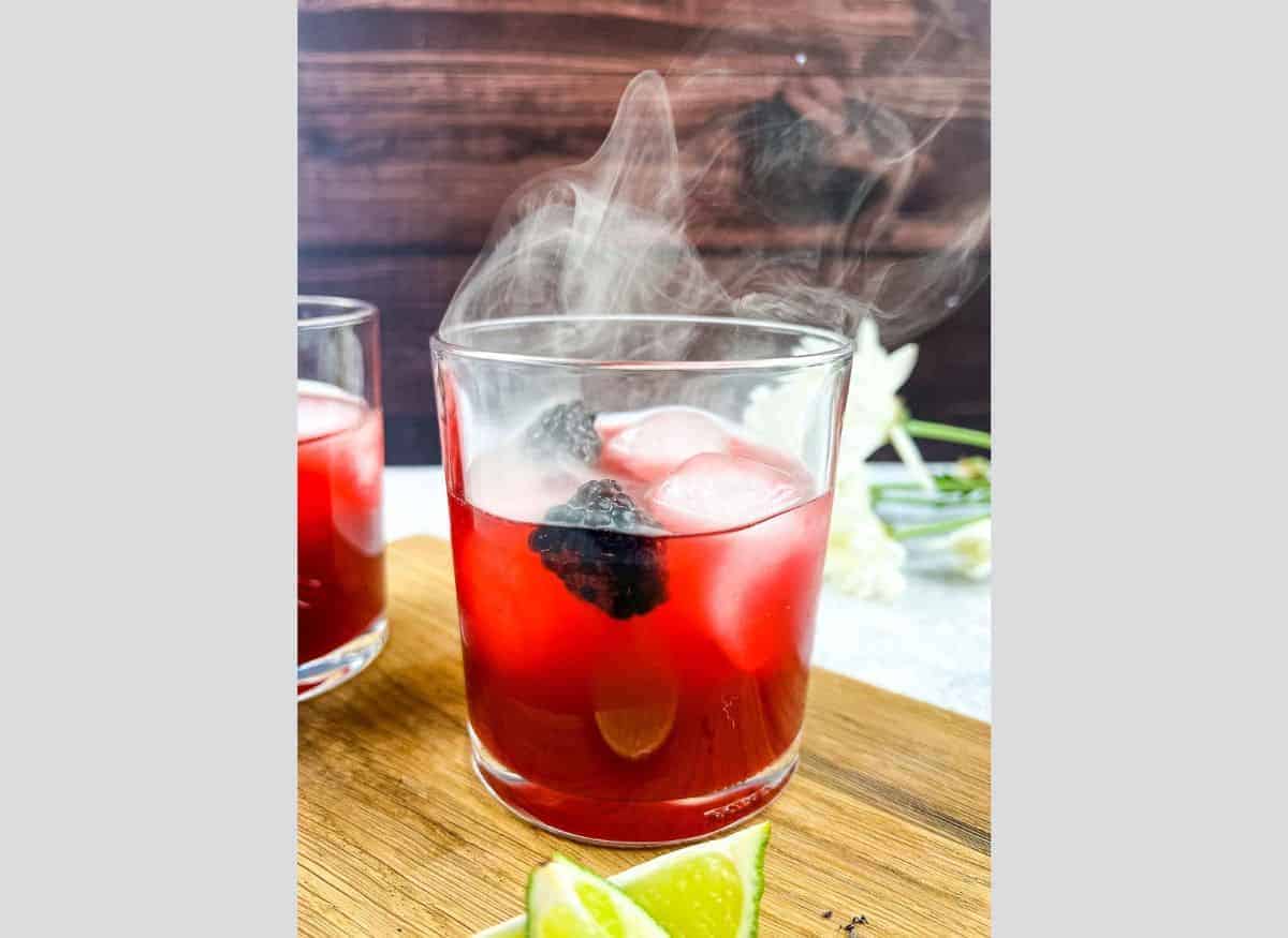 Smoked Blackberry Margarita with smoke coming out the top of the glass.