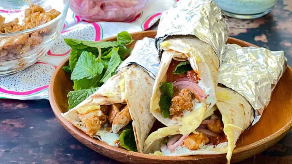 Chicken wraps in foil on a wooden table.
