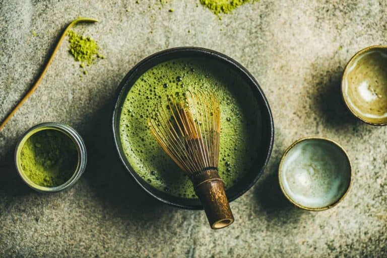A bowl of green tea with a whisk.