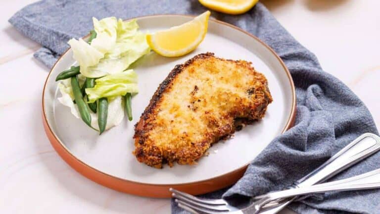 Panko pork chop on plate with greens.