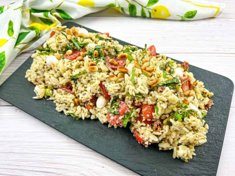 Orzo salad resting on a dark plate.