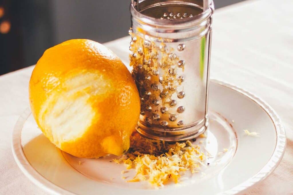 A lemon and grater on a plate.