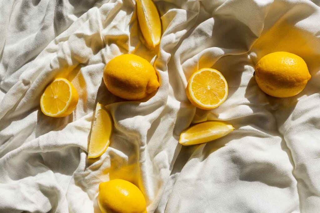 A bunch of lemons on a white sheet.