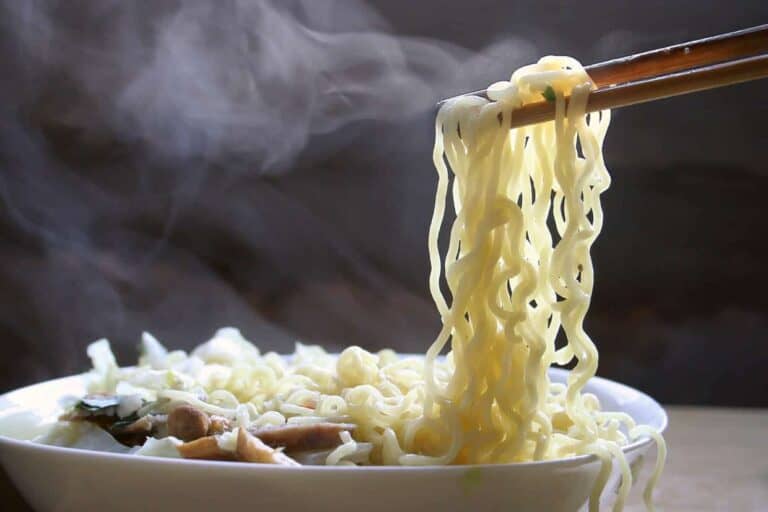 A bowl of noodles with chopsticks in it.