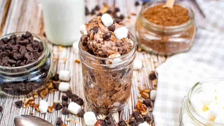 A jar of chocolate pudding with marshmallows and chocolate chips.