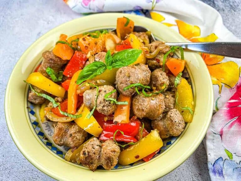 A bowl of meatballs and peppers with a fork.