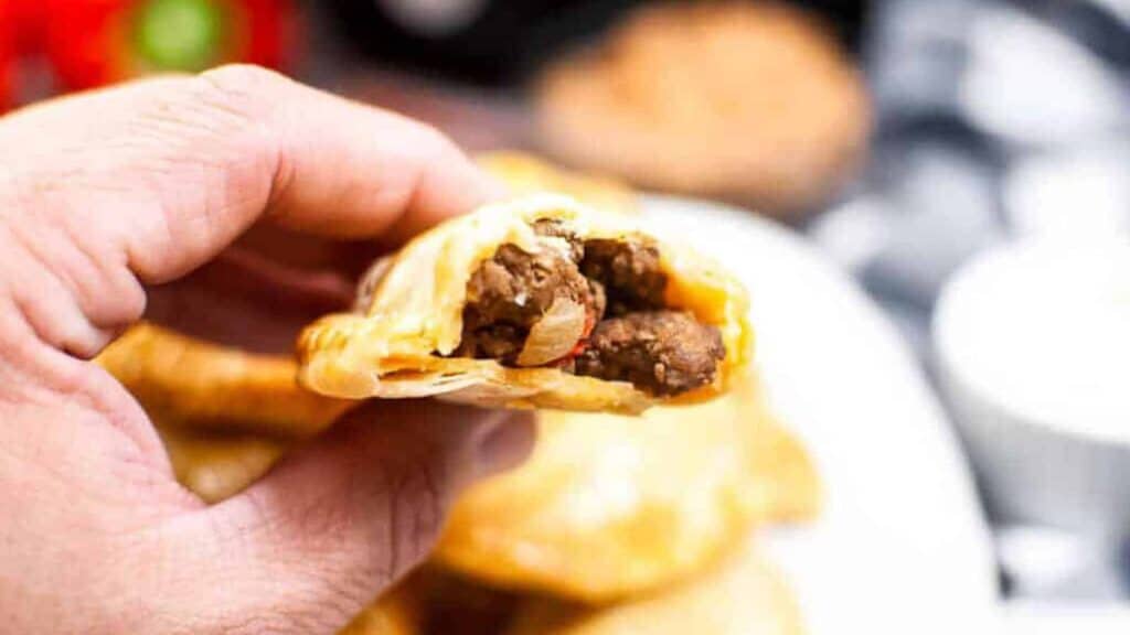 A hand holding a meat filled pastry.