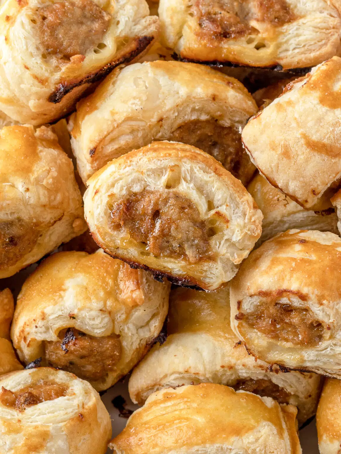 Close up of the flaky puff pastry layers and chicken sausage filling in these delicious baked chicken sausage rolls.