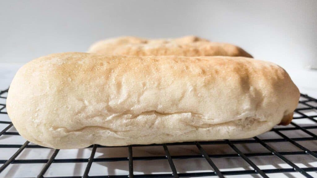 Two loaves of bread sitting on a cooling rack.