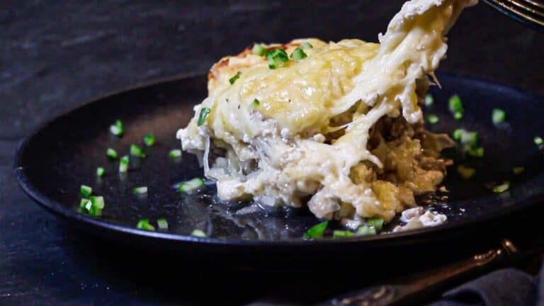 A fork is being used to eat a casserole on a plate.