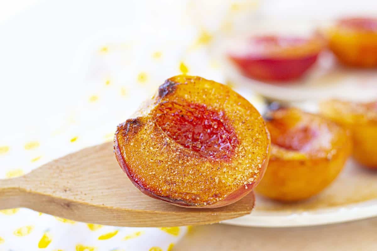 Air-fried peaches on a plate with a wooden spoon.