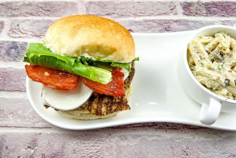 A burger and a bowl of pasta on a plate.