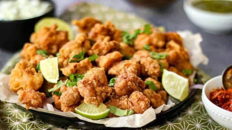 Fried chicken on a plate with lime wedges.