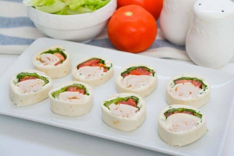 Chicken wraps with tomatoes and lettuce on a white plate.