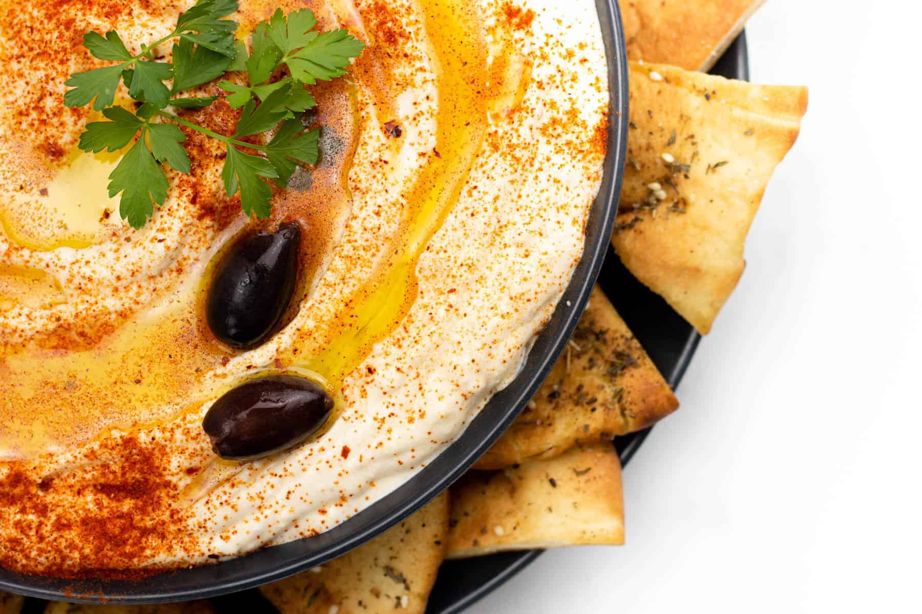 A bowl of whipped feta dip with crackers and olives.