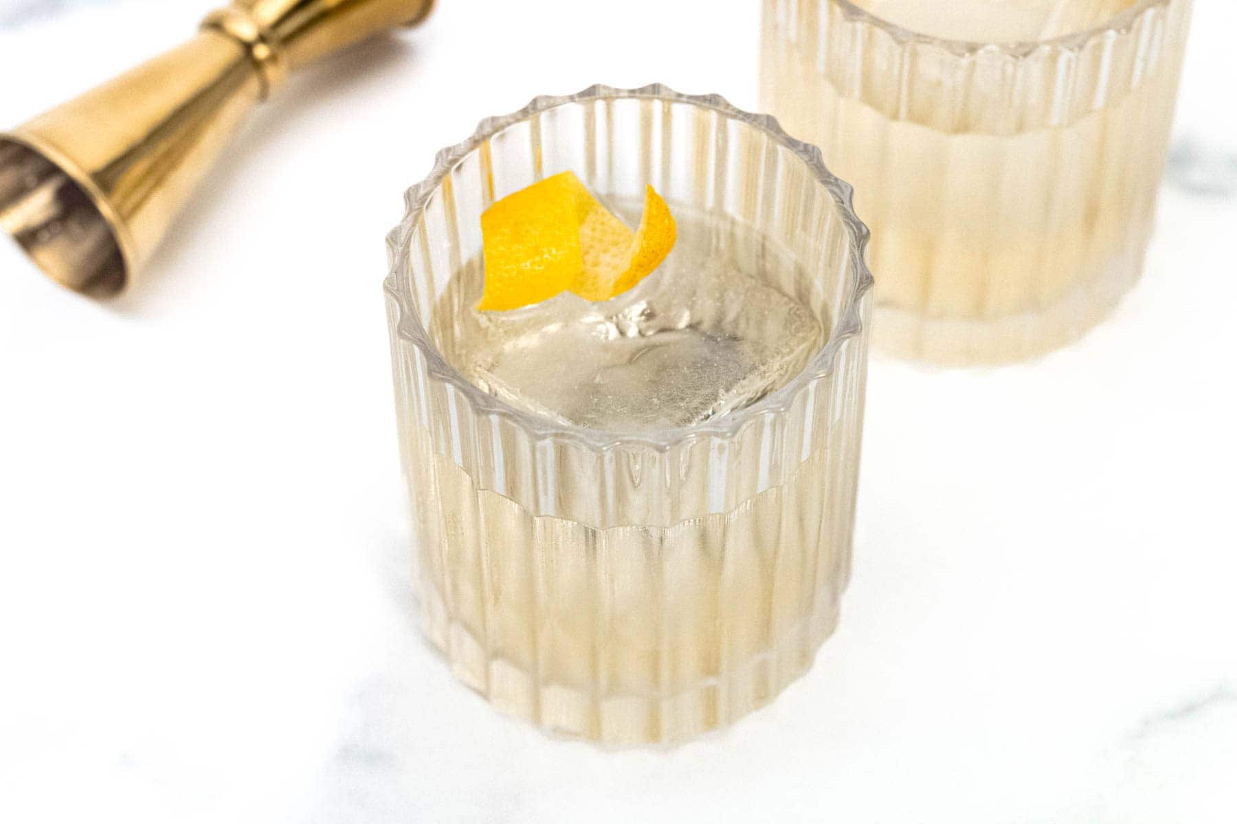 Two glasses of White Negroni on a marble table.