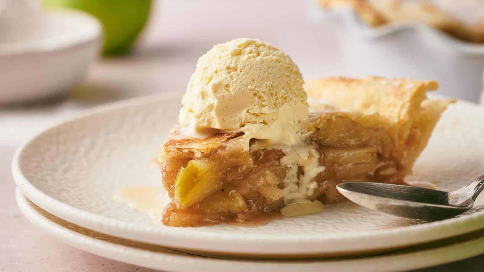 A slice of apple pie on a plate with a scoop of ice cream.