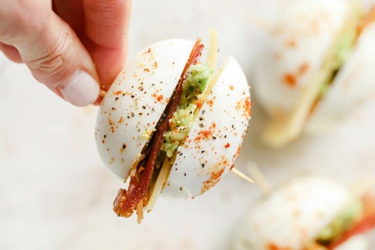 A person holding a skewered bacon egg and cheese breakfast slider.