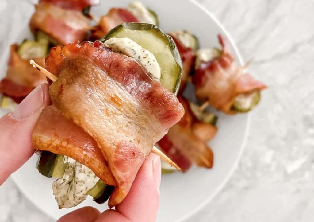 Bacon wrapped pickles on a plate.