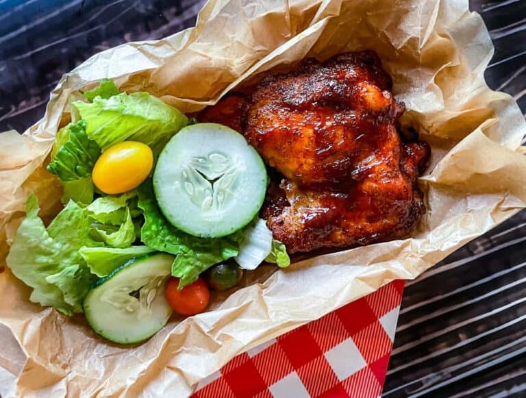 Winter dinner of bbq chicken in a paper boat served with salad and vegetables.