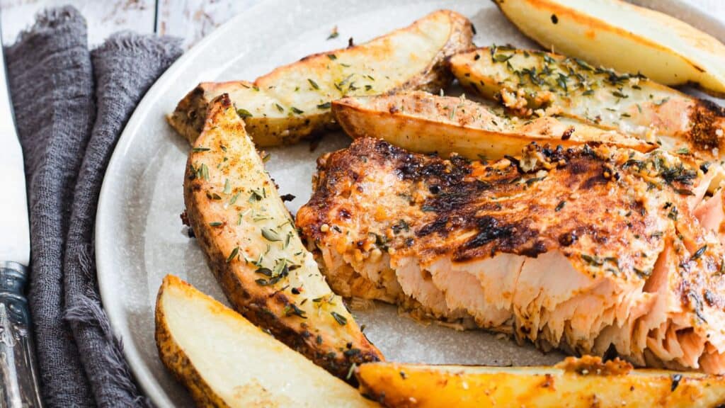 Grilled salmon with potatoes and herbs on a plate.