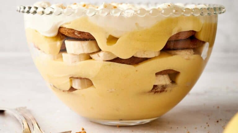 Banana trifle in a bowl with whipped cream and banana slices.