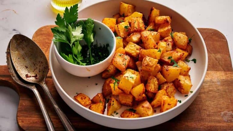 Roasted potatoes in a bowl with a spoon and parsley.