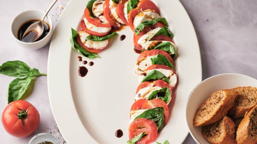 A plate with tomatoes, basil and bread on it.