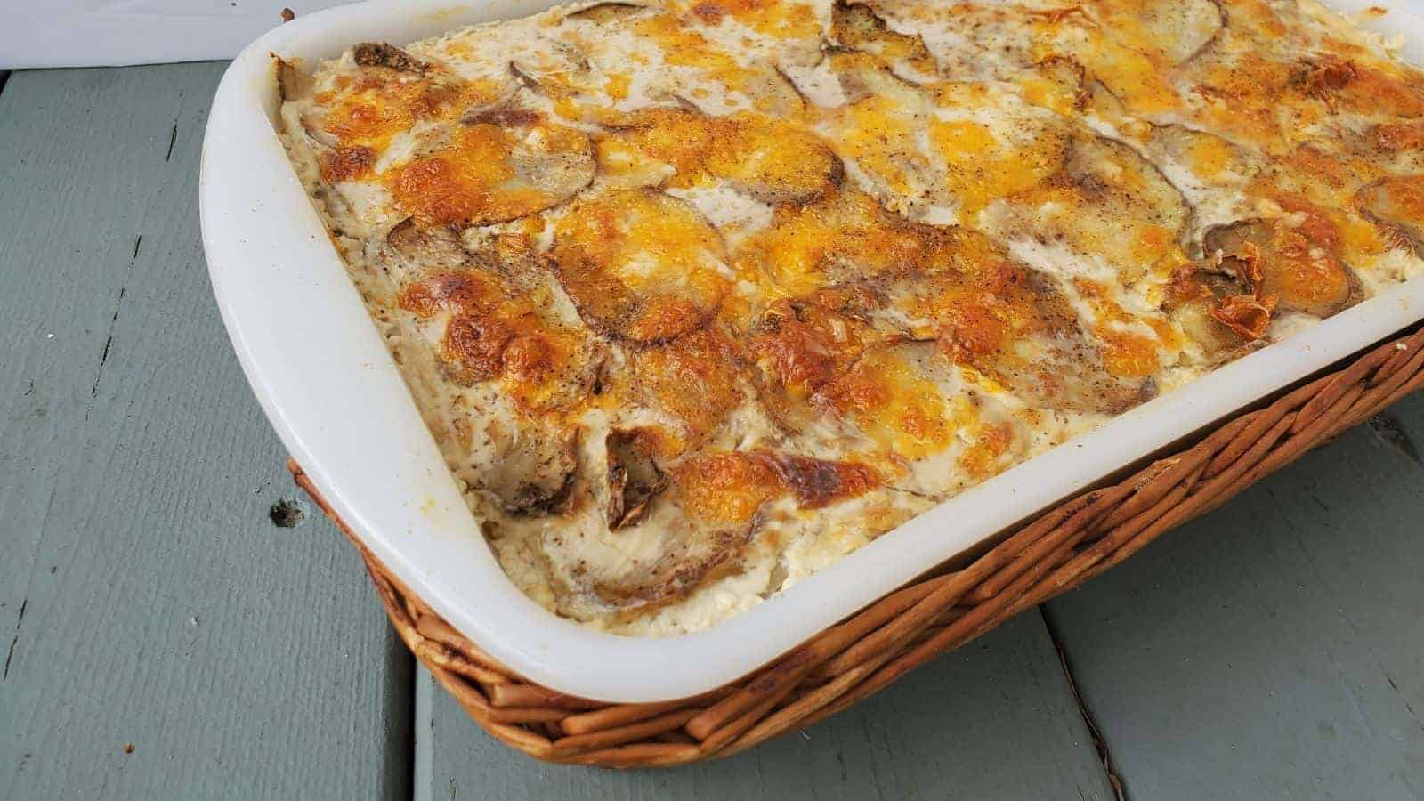 Cheesy scalloped potatoes in a casserole dish on a blue wooden table.