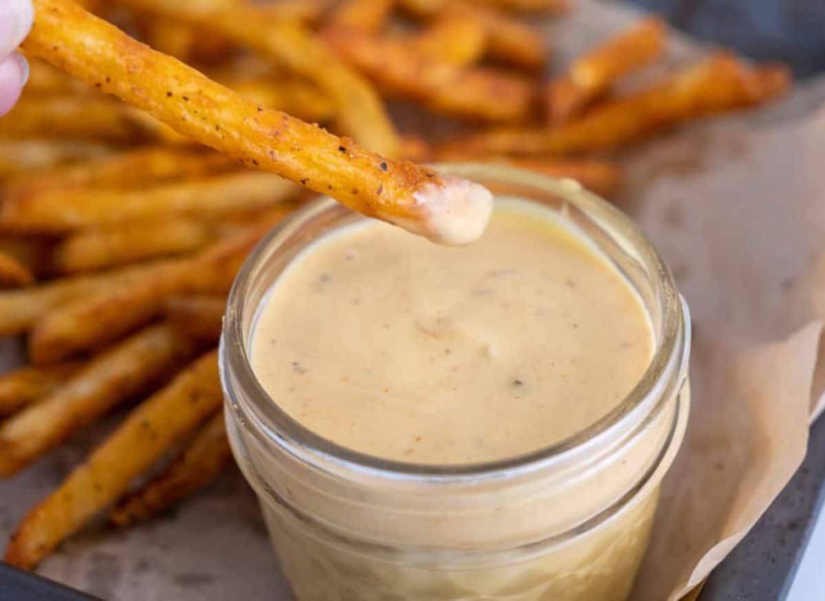 Dipping a French fry into a jar of copycat chick fil a sauce.