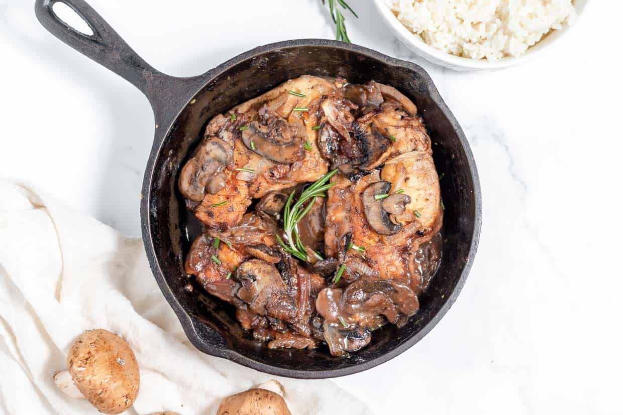 Roasted chicken with mushrooms and potatoes in a cast iron skillet.
