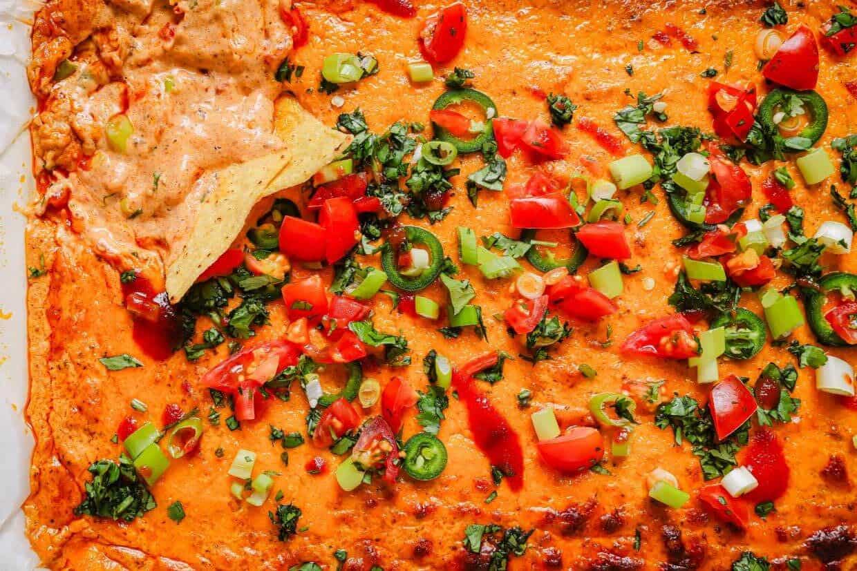 Chili cheese dip in a baking dish with toppings.