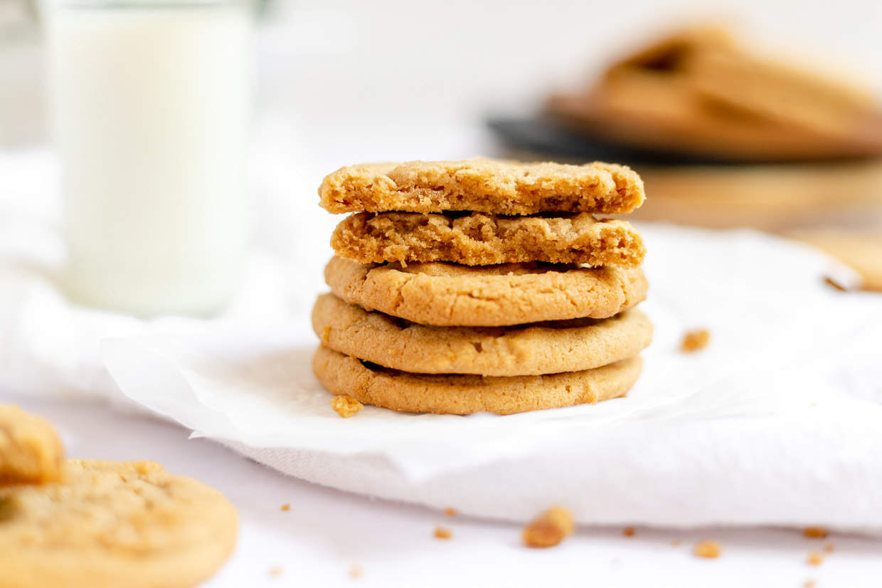 A stack of Biiscoff cookies next to a glass of milk, the perfect treat for a cozy winter evening.