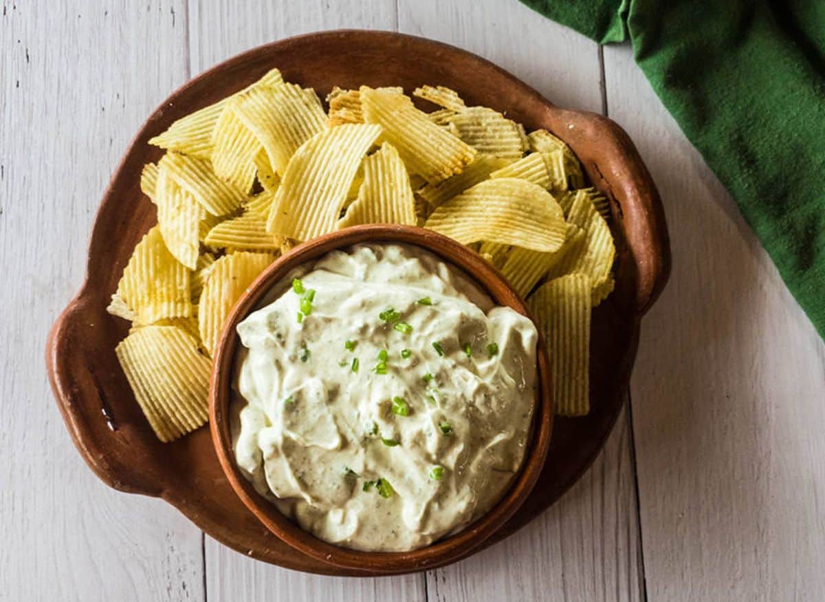 A picture of the best chip dip with potato chips on a tray.