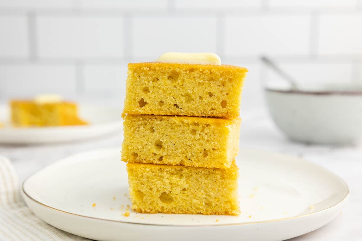 Cornbread stacked on a plate with butter.