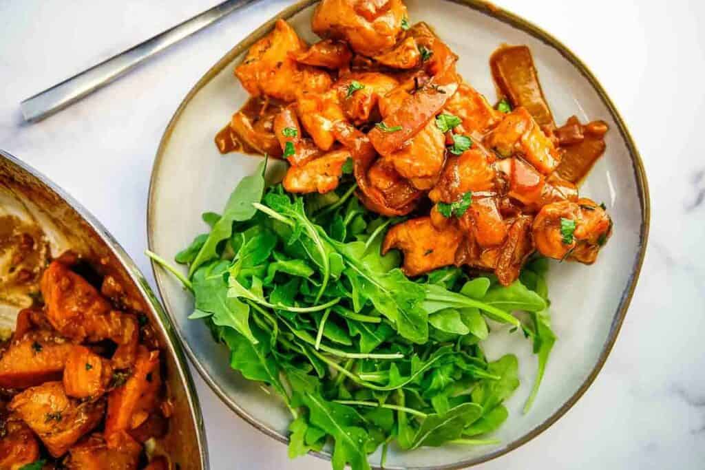 A plate of chicken and greens with a fork.