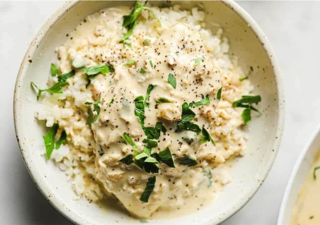 A bowl of cauliflower rice with creamy garlic chicken.