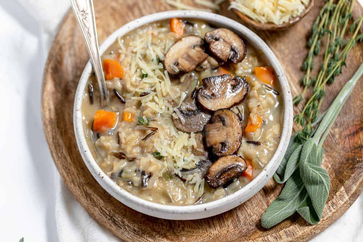 Wild rice and mushroom soup in a white bowl with sprigs of sage.