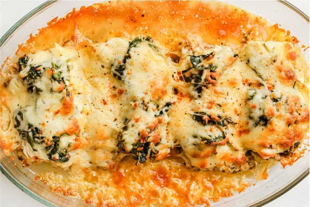 A casserole dish filled with chicken, spinach and cheese.
