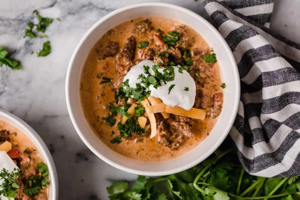 Two bowls of crock pot taco soup with cheese and sour cream.