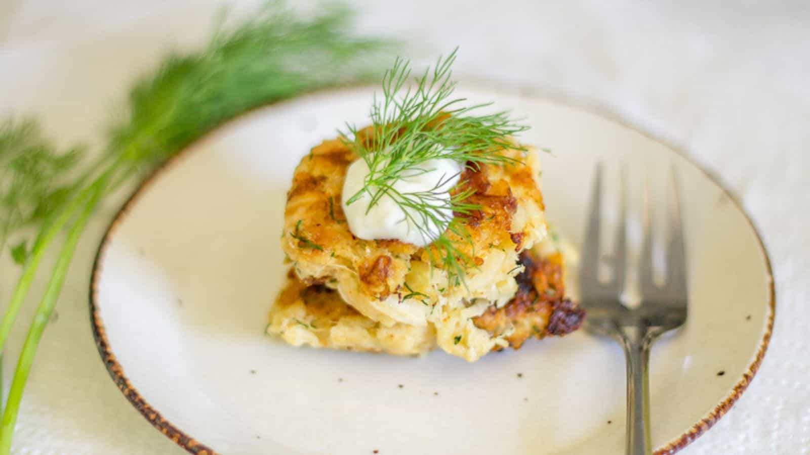 A plate of dill cakes with sour cream and dill.