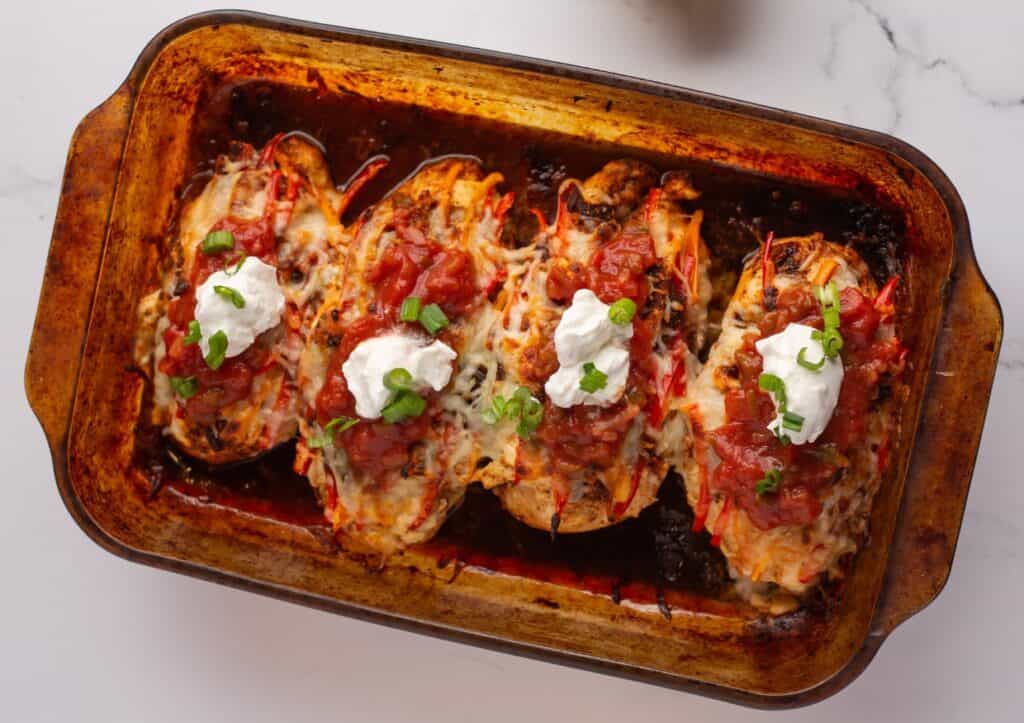 Fajita baked chicken in a baking dish with salsa and sour cream.